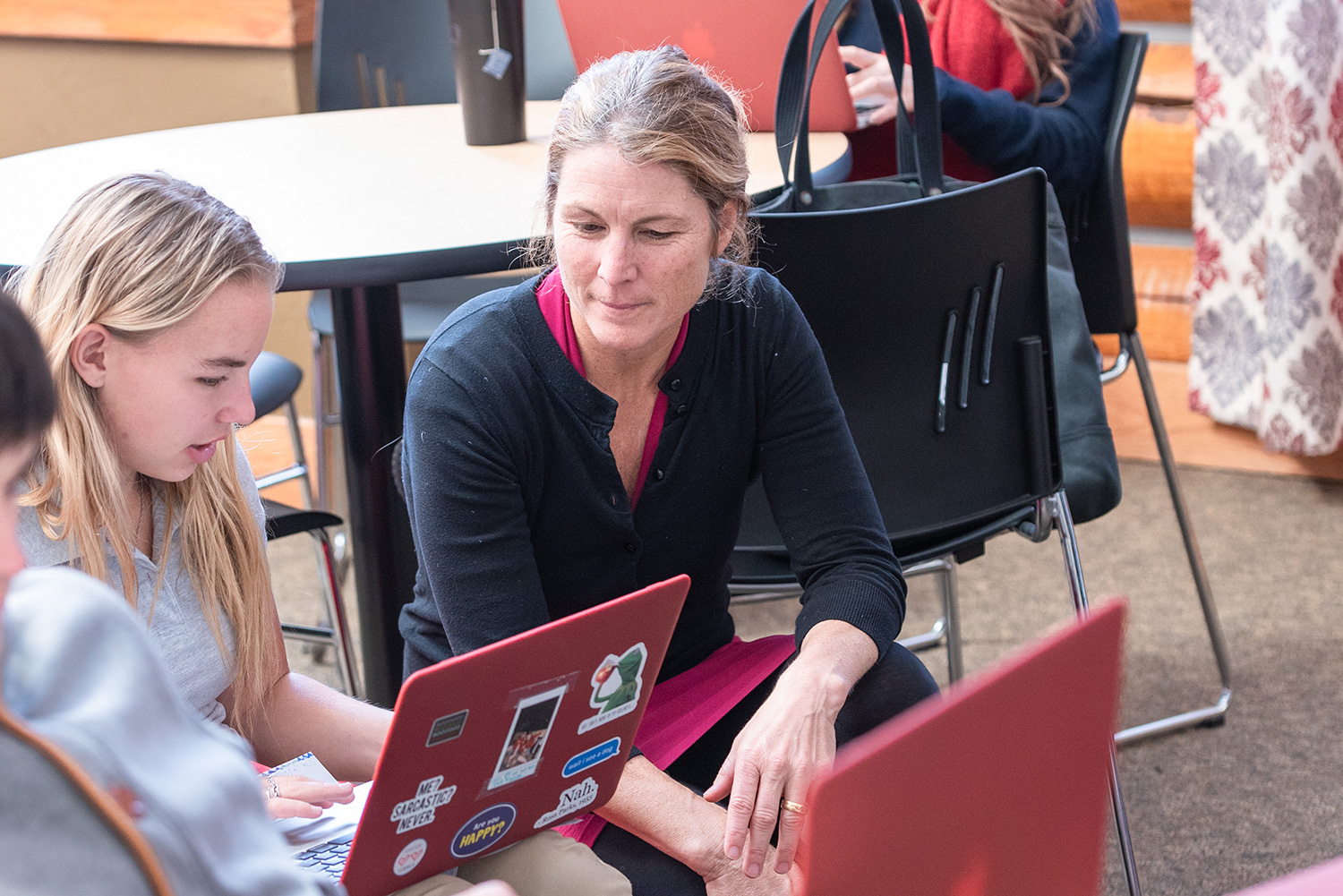 female teacher with female student working on laptop