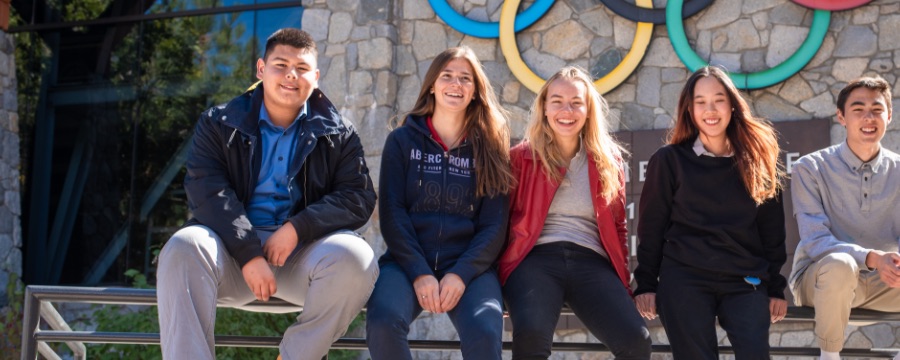 5 students sitting on railing outdoors